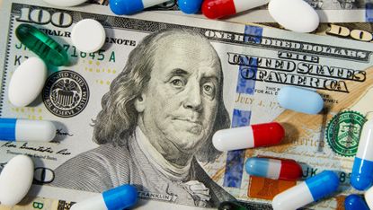 Close-up shot of different sized prescription pills spilled on a background of US dollars