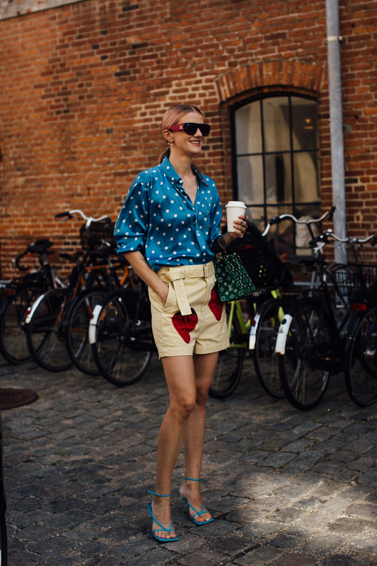 a woman at Copenhagen in Fashion Week wearing blue polka dot shirt, with yellow shirt, and blue heels