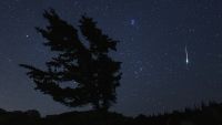 meteor in background with tree in front