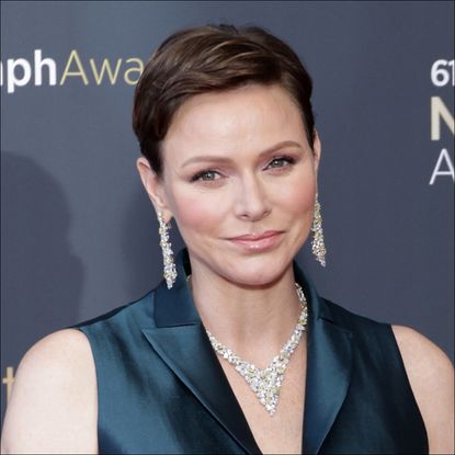 Princess Charlene of Monaco wears a black shirt dress with a large diamond necklace and matching drop earrings while her hair is brunette and cropped short