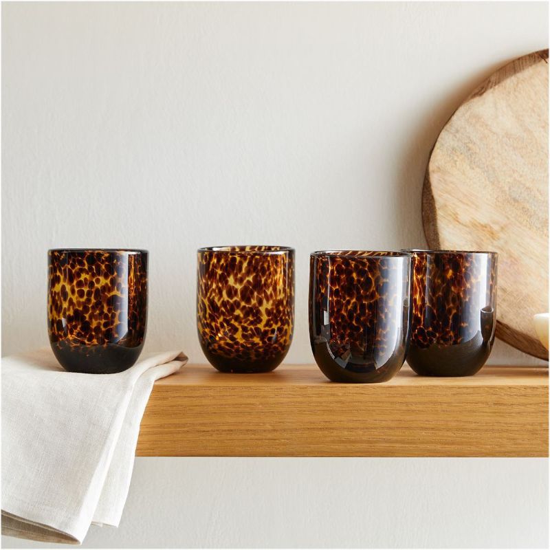 Four old fashioned tortoiseshell drinking glasses on a wooden shelf, for the best tortoiseshell homeware.