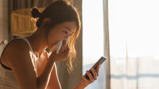 Do air purifiers help with allergies? Image shows woman holding tissue to her nose