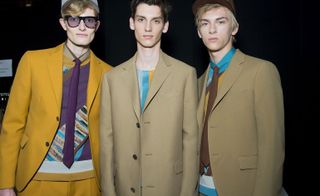 Three male models wearing clothing by Salvatore Ferragamo in brown shades.
