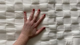 A hand touching the surface of the Levitex mattress topper