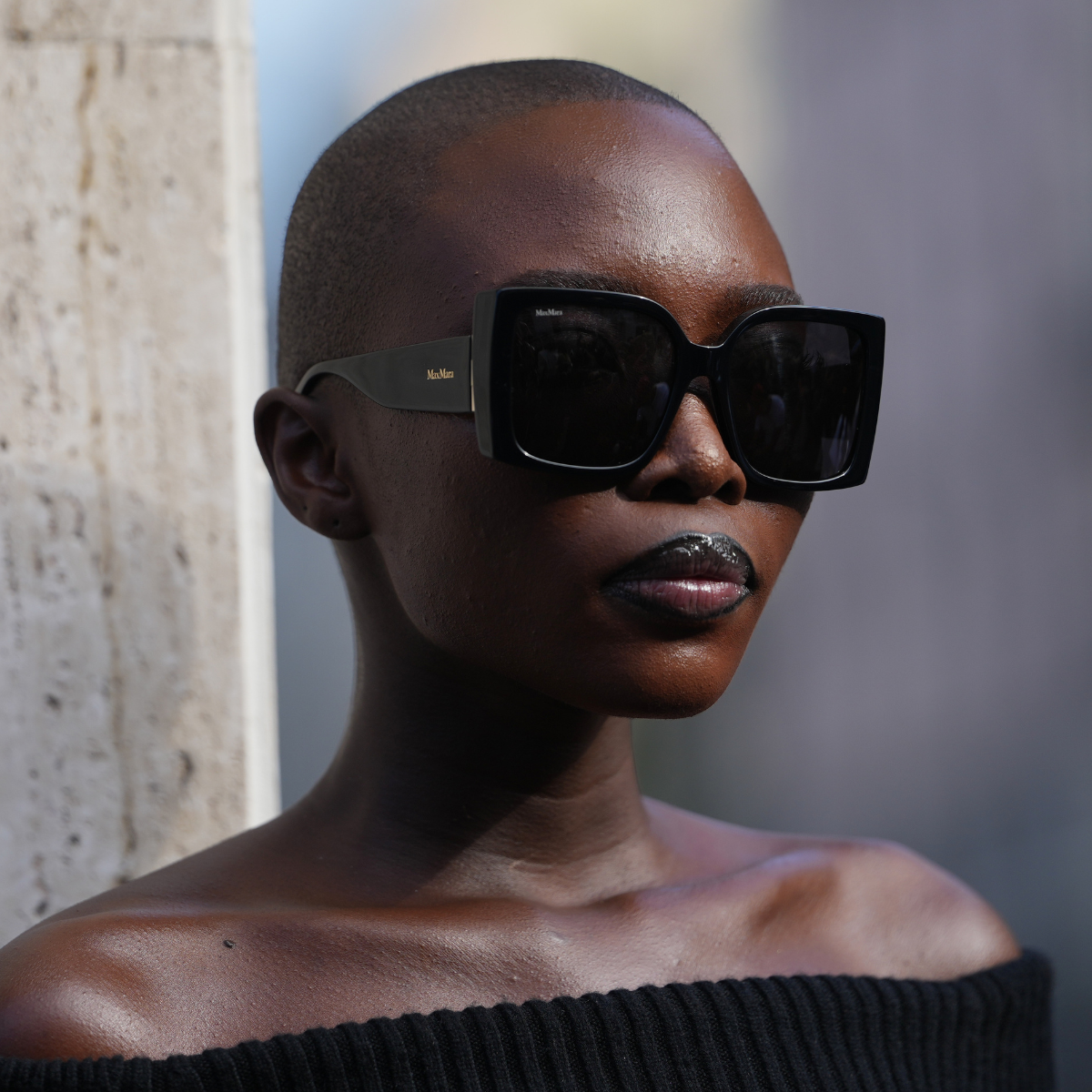 Concealers for dark skin Amina Seck wears a shaved close-cropped black hairstyle, oversized square black sunglasses with thick temples and dark lenses, a black ribbed knit off-the-shoulder sweater showing bare shoulders, outside Max Mara, during Milan Fashion Week - Womenswear Spring/Summer 2026, on September 25, 2025 in Milan, Italy