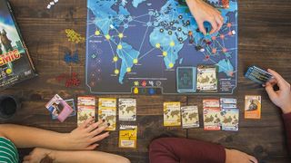 Birds' eye view of people playing Pandemic board game