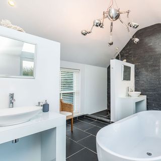 bathroom with white walls black flooring and bathtub