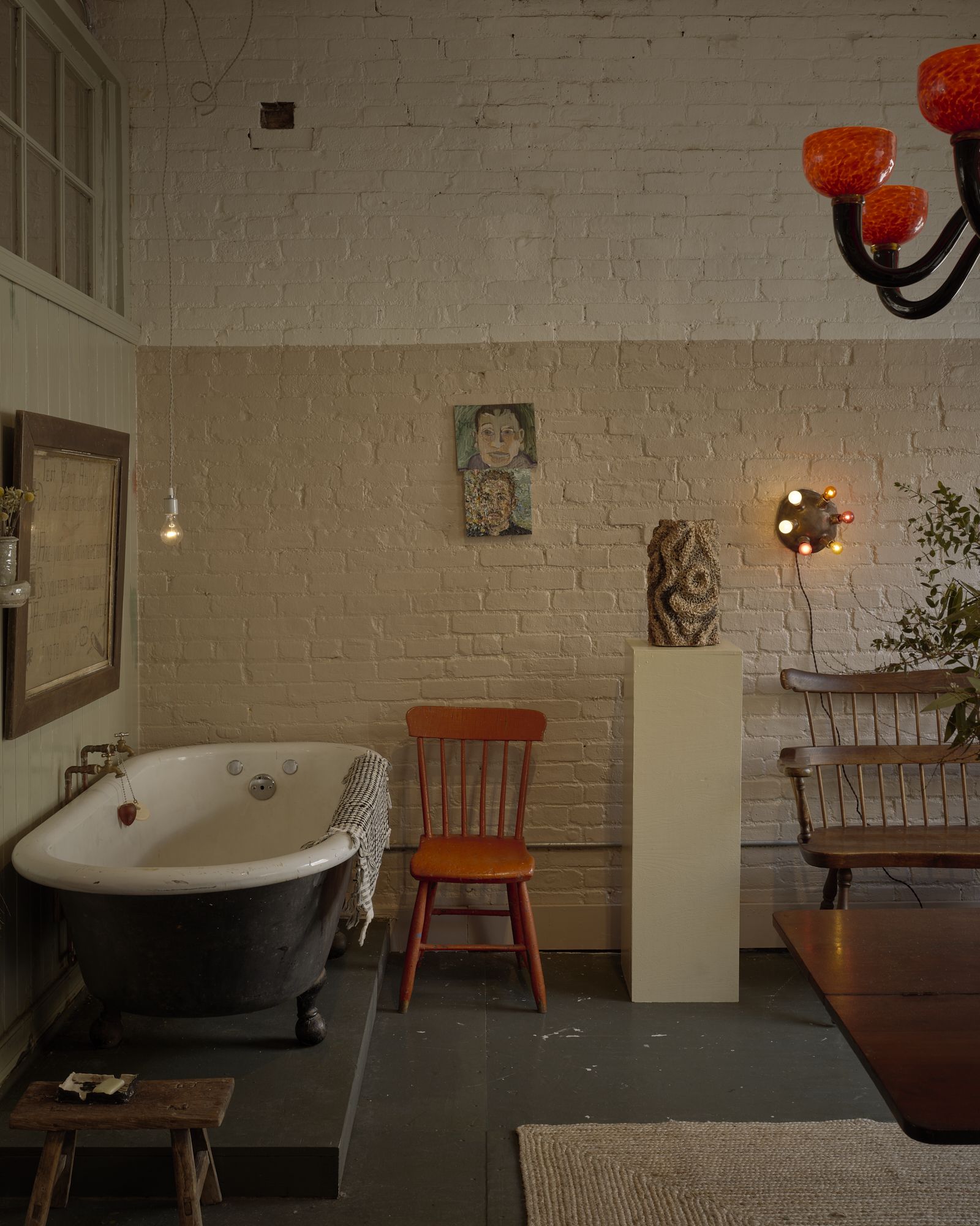 A gallery-like home filled with quirky sculptures in pastel tones, white-washed and cream-painted walls, and organic shaped furniture, including chairs, stools, and coffee tables, along with artworks.