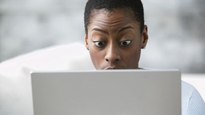 A female investor looks at her laptop and appears surprised by what she's seeing.