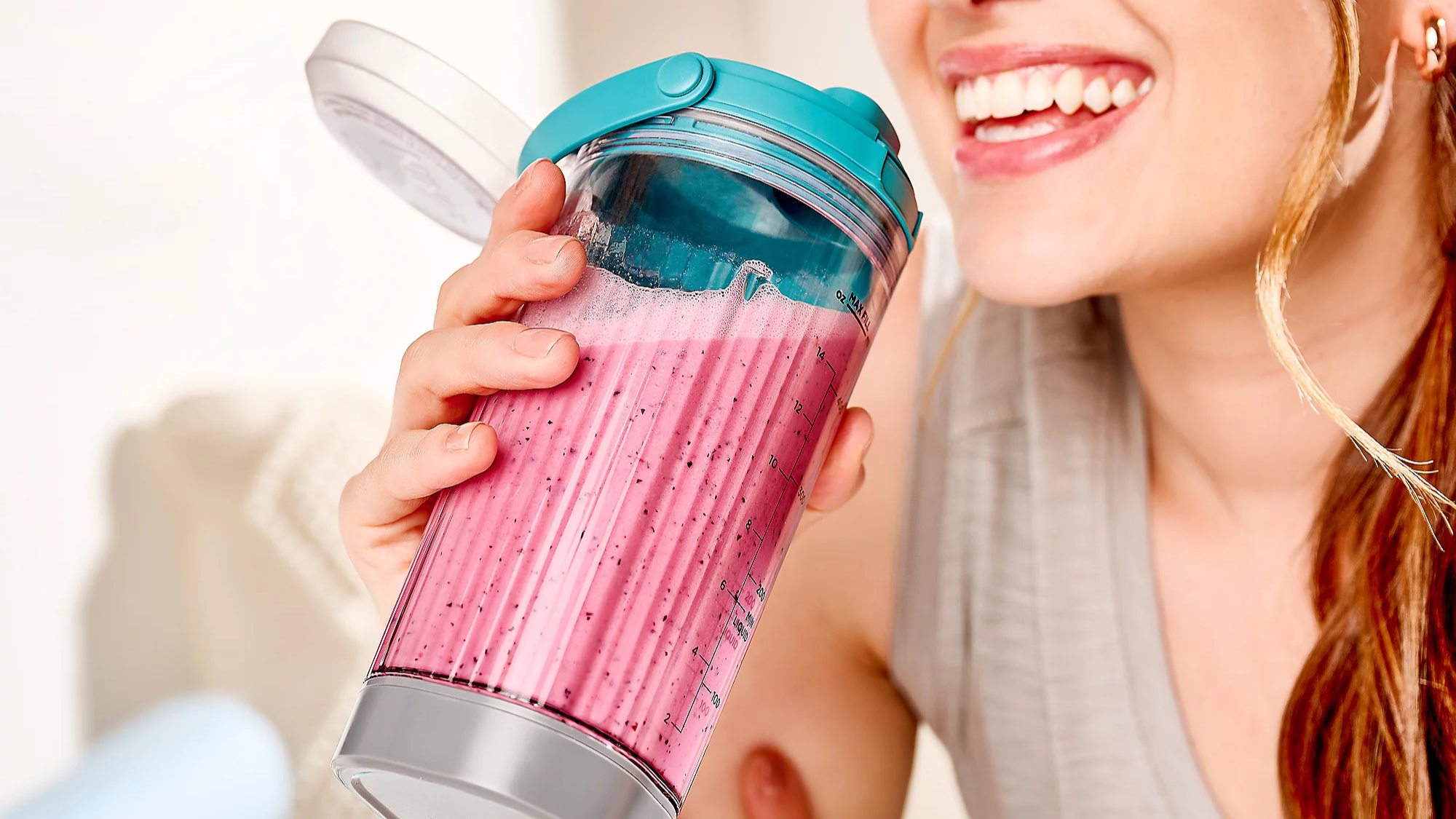 A woman drinking a smoothie from a Ninja Blast 18-oz Portable Rechargeable Blender