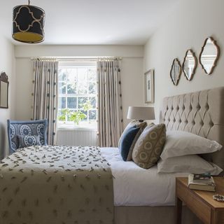 guest room with white walls and white window with curtains and bedding with cushions and throw