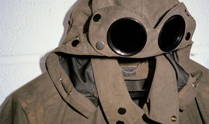 Khaki brown coloured coat with goggles incorporated into in the hood, metal press studs. white background