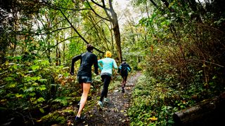 Three women running in a forest