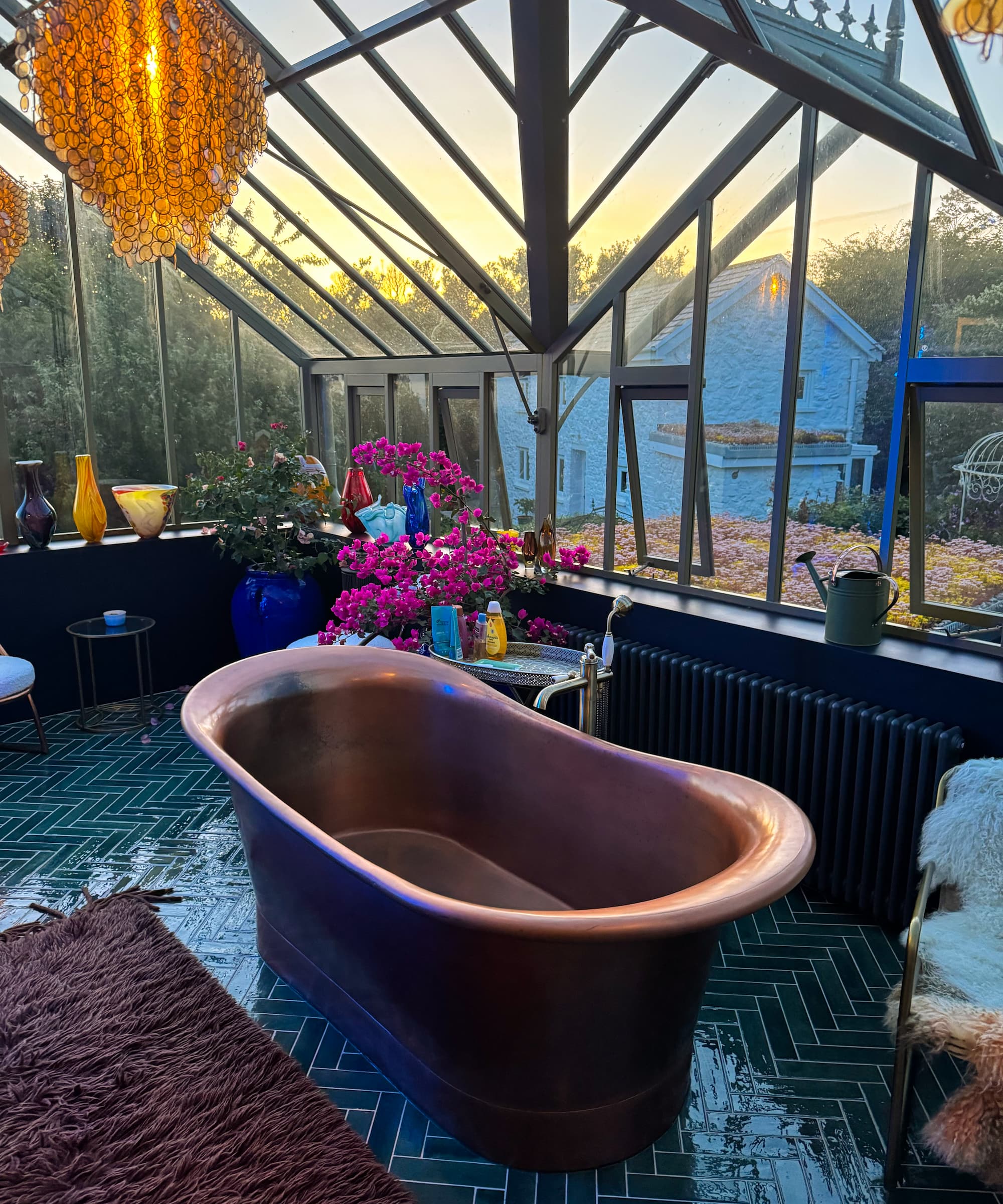 A brass bath in a greenhouse and green tiled flooring