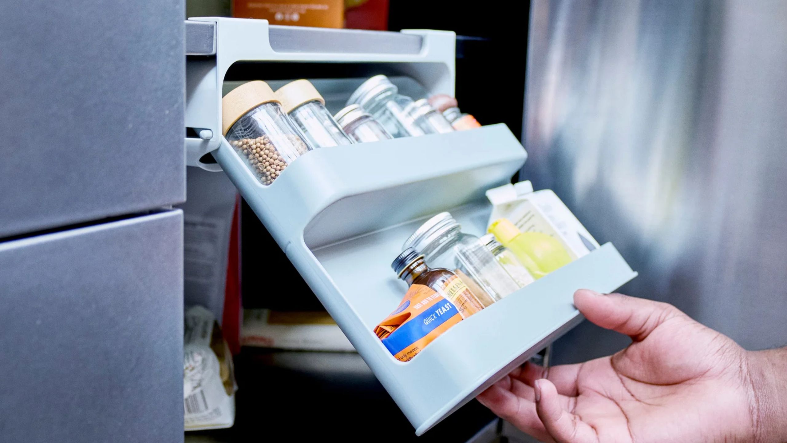 A pull out rouble rack spice storage shelf being pulled out from beneath a cabinet shelf. 