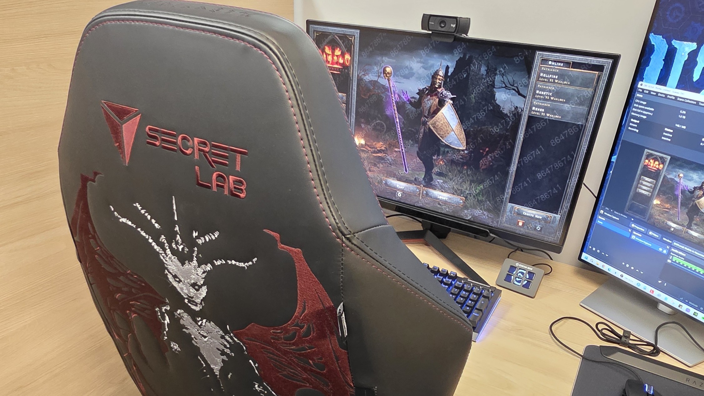A black gaming chair with a demonic figure embossed onto the back, sits in front of a desk with a gaming computer.