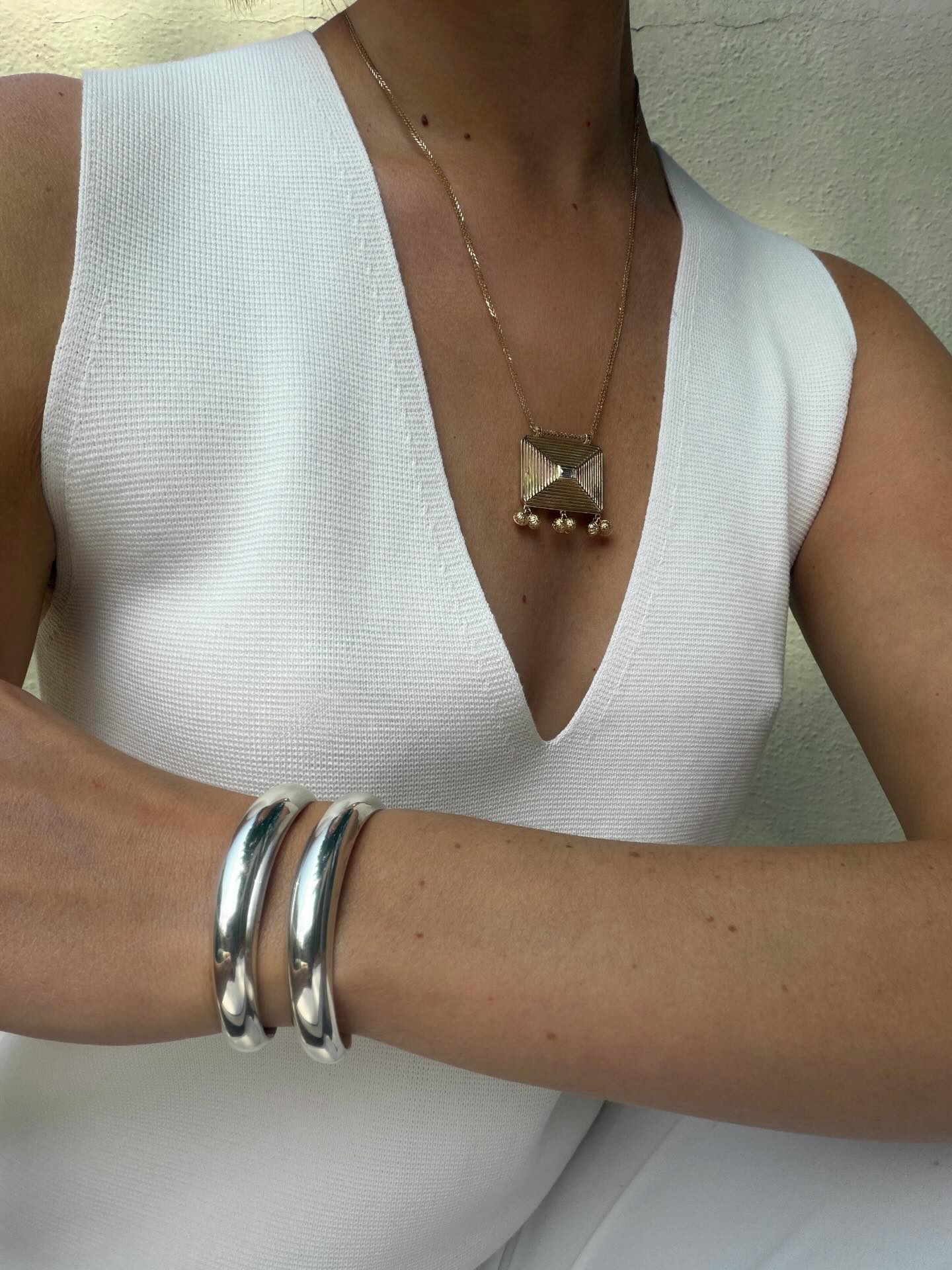 Christie wearing silver cuff bracelets and a gold necklace