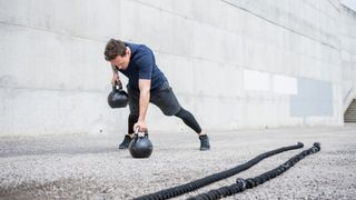Man performs renegade row with kettlebells