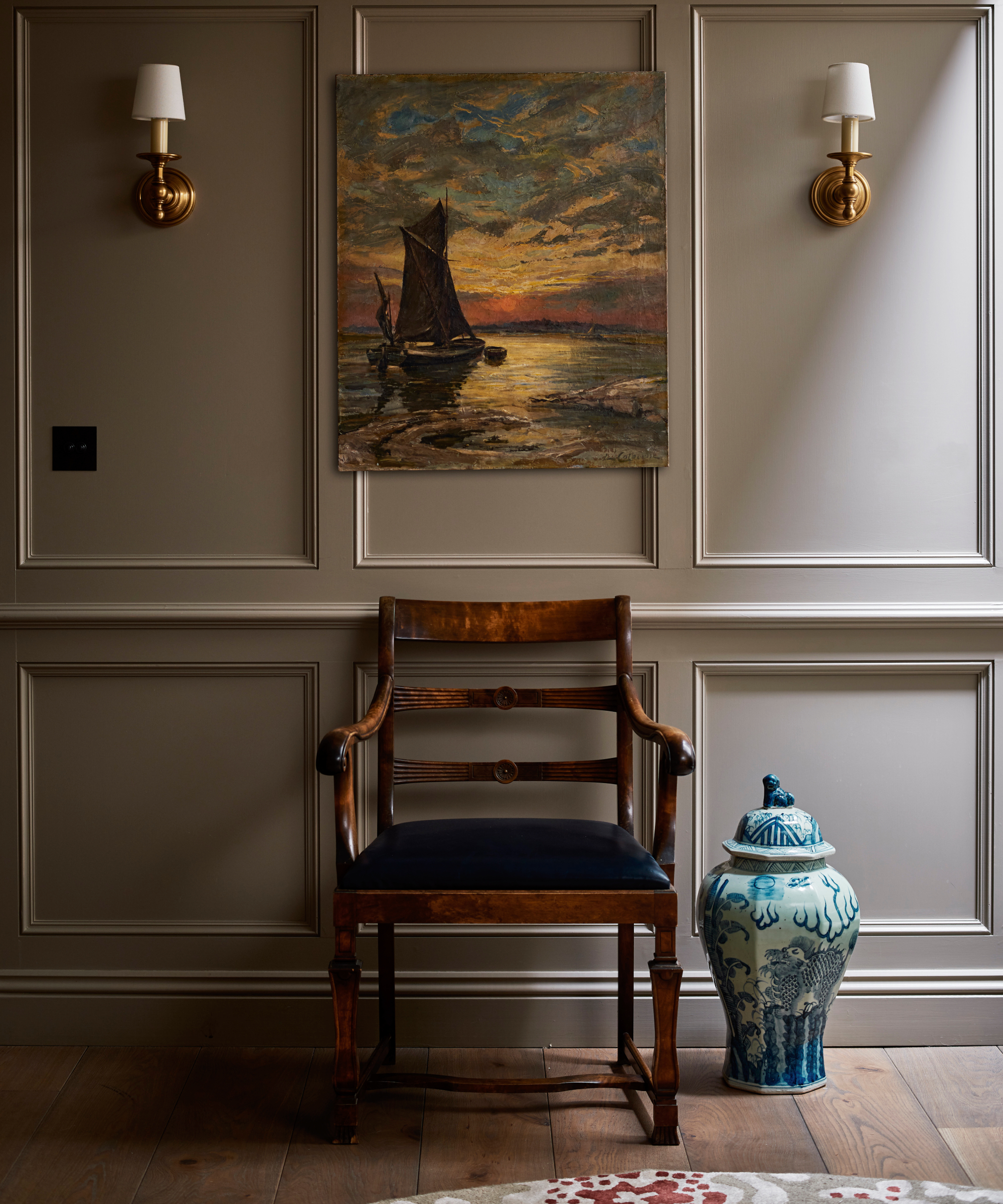 hallway with wood panelling, chair, artwork above and wall lights either side