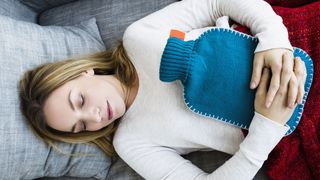 A woman sleeps with a blue hot water bottle