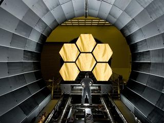 NASA engineer Ernie Wright holds a dramatic pose in front of the first six flight-ready James Webb Space Telescope's primary mirror segments at NASA's Marshall Space Flight Center. Engineers began final round-the-clock cryogenic testing on the mirrors bef
