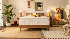 The TEMPUR-Adapt Topper on a wooden bedrframe in a beige boho bedroom with warm lighting and abstract art on the walls