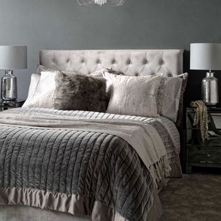 bedroom with grey wall lamp and mattress with cushions