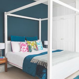 bed with side pillars next to white wardrobe