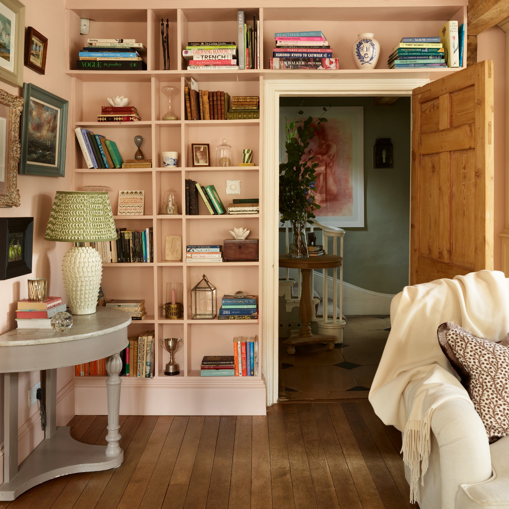 A pink living room with built-in bookshelves displaying books and decor