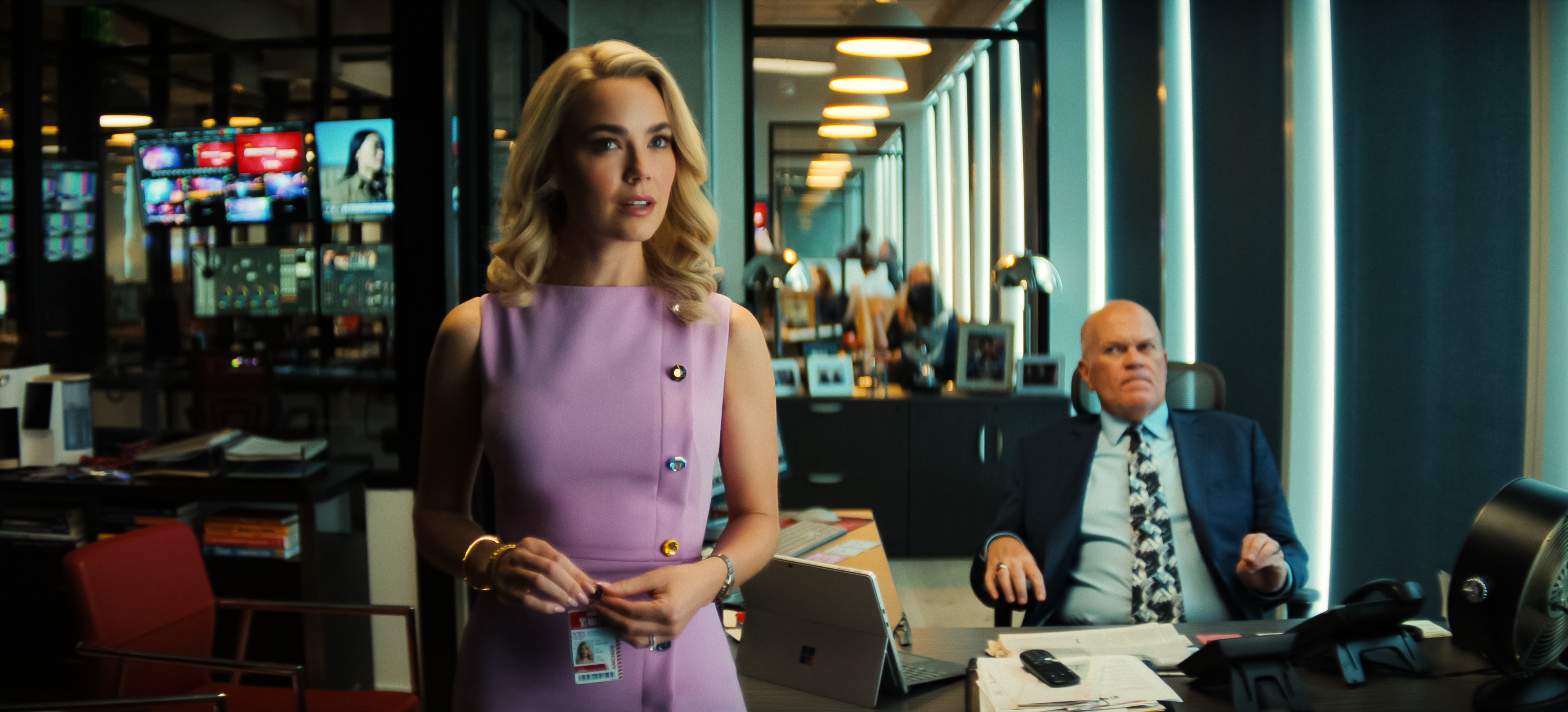 Rebecca Rittenhouse as Lexi and Mike Pniewski as Jim Pruss looking up at a tv in a local tv news channel's office in netflix's His &amp;amp; Hers