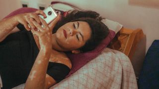Woman using her phone in bed - stock photo