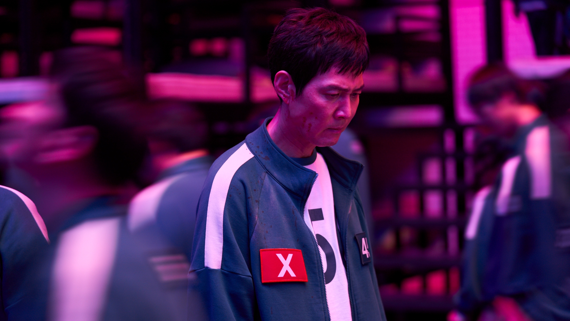 Gi-hun looks down with an X on his jacket in Squid Game season 2