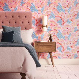 pink and blue patterned wallpaper in a pink bedroom, with a pink headboard, green bedding, and pink carpet