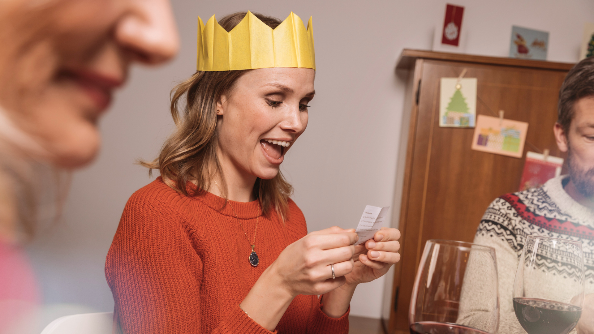 Woman with paper crown reading a poem from her Christmas cracker