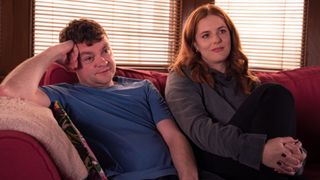 Angus (SCOTT FLETCHER), Amber (JENNY HULSE) sitting on a sofa in River City