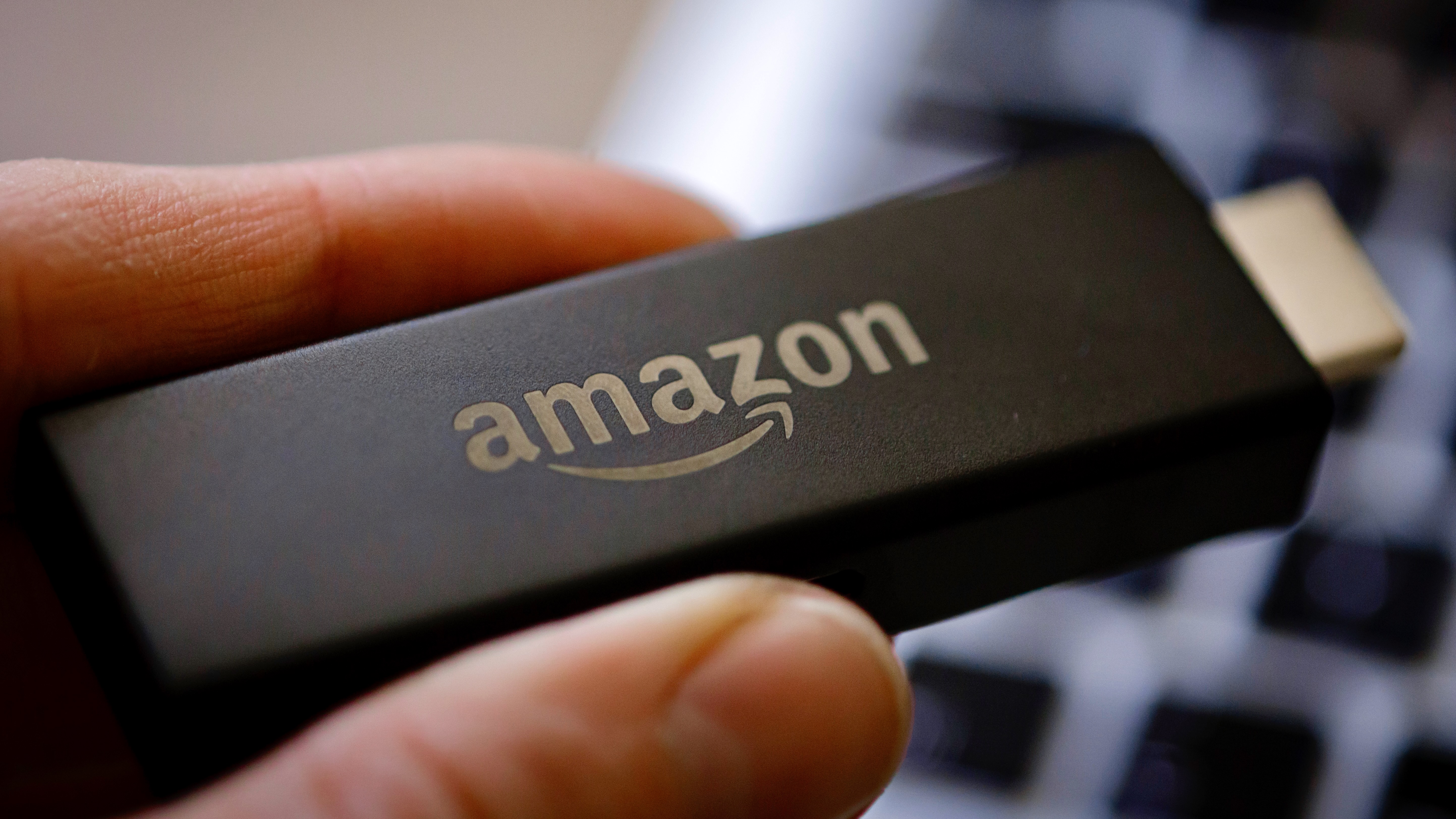 A close-up of an Amazon Fire TV Stick being held between two fingers.