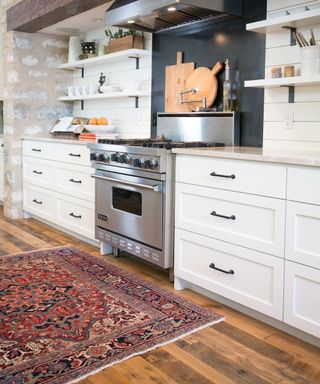 white kitchen with colorful rug and wooden floors and steel range cooker