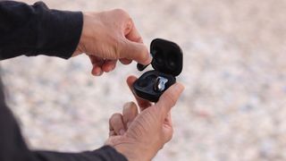 Someone holding a pair of the Samsung Galaxy Buds Live and putting the buds into the charging case.