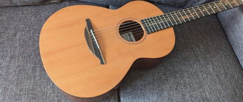 A Sheeran by Lowden W05 acoustic guitar lying on a grey sofa