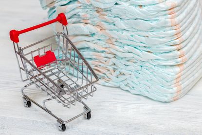 tiny shopping card beside large pile of diapers