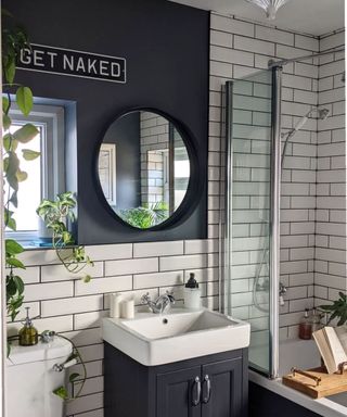 Black bathroom with round mirror and wall sign