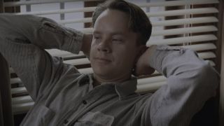 Tim Robbins leans back with a face of satisfaction in The Shawshank Redemption.