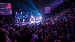 A band performs at Unite 180 Church as the stage is lit with Stage Plus lighting solution.