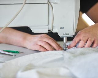woman's hands at a sewing machine, sewing fabric
