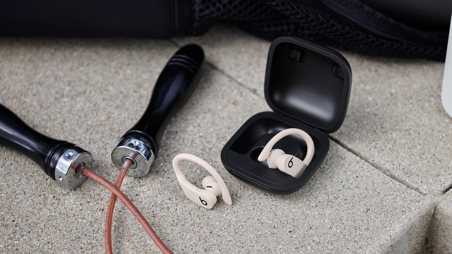 The Beats Powerbeats Pro true wireless earbuds in white, inside a black charging case next to a skipping rope