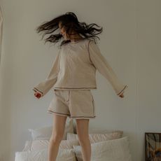 A woman jumping on the bed; fluffy pillows and a gua sha.