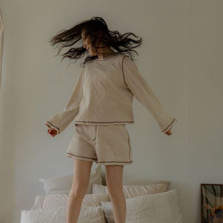 A woman jumping on the bed; fluffy pillows and a gua sha.