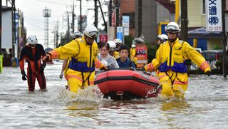 Rescue workers transport people in a rubber boat in Oyama in Tochigi prefecture, north of Tokyo on Sept. 10, 2015, just after torrential rains flooded rivers and triggered landslides.