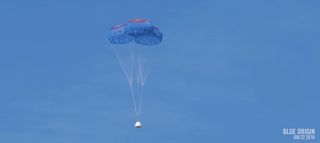 Blue Origin's New Shepard crew capsule hangs suspended under its three main parachutes as it approaches Earth after a successful launch and landing test flight over West Texas on Jan. 22, 2016.