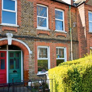 Exterior of brick terraced house with red and green painted doors